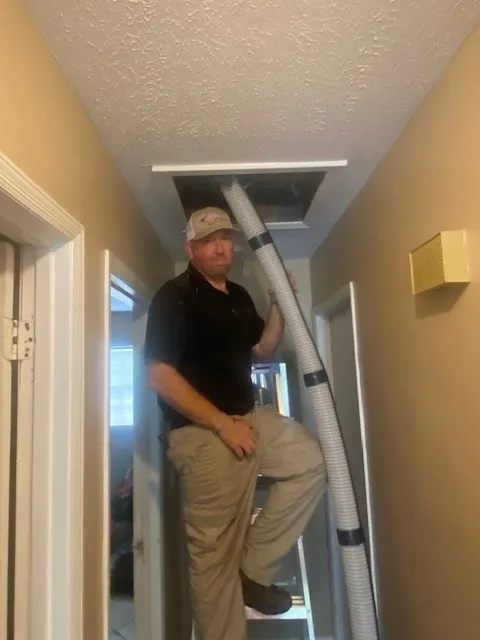 A Jarrod's technician climbing to an attic hatch to inspect it